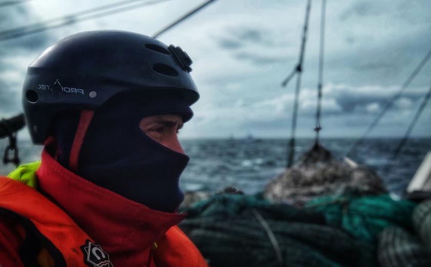 Close up or a man in protective and hi-vis clothing on a boat